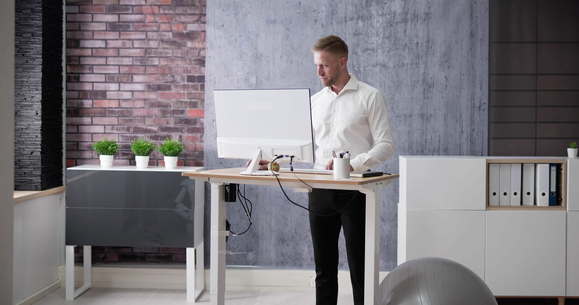 Man Using Adjustable Height Standing Desk In Office
