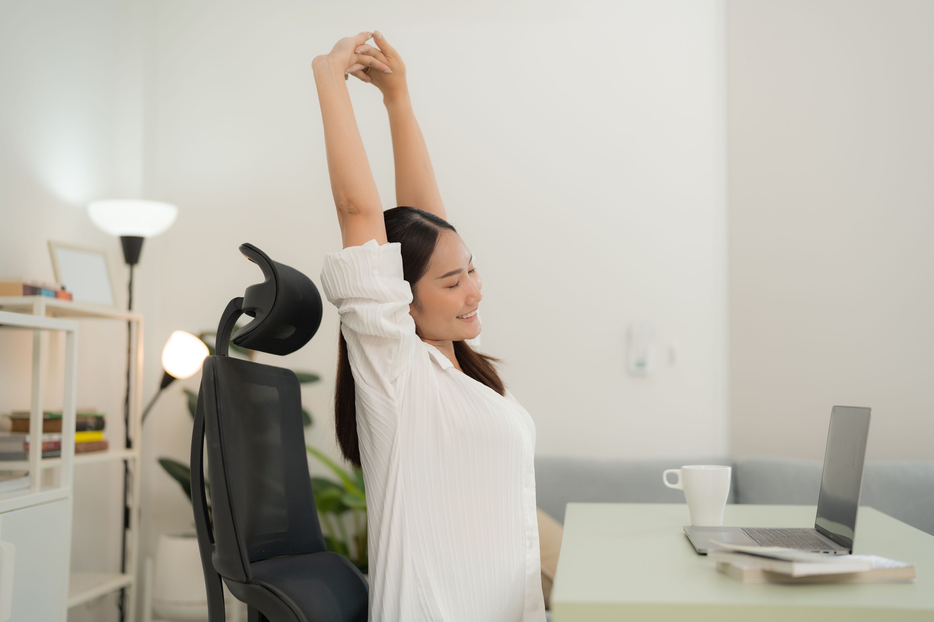 Young woman stretching while working from home