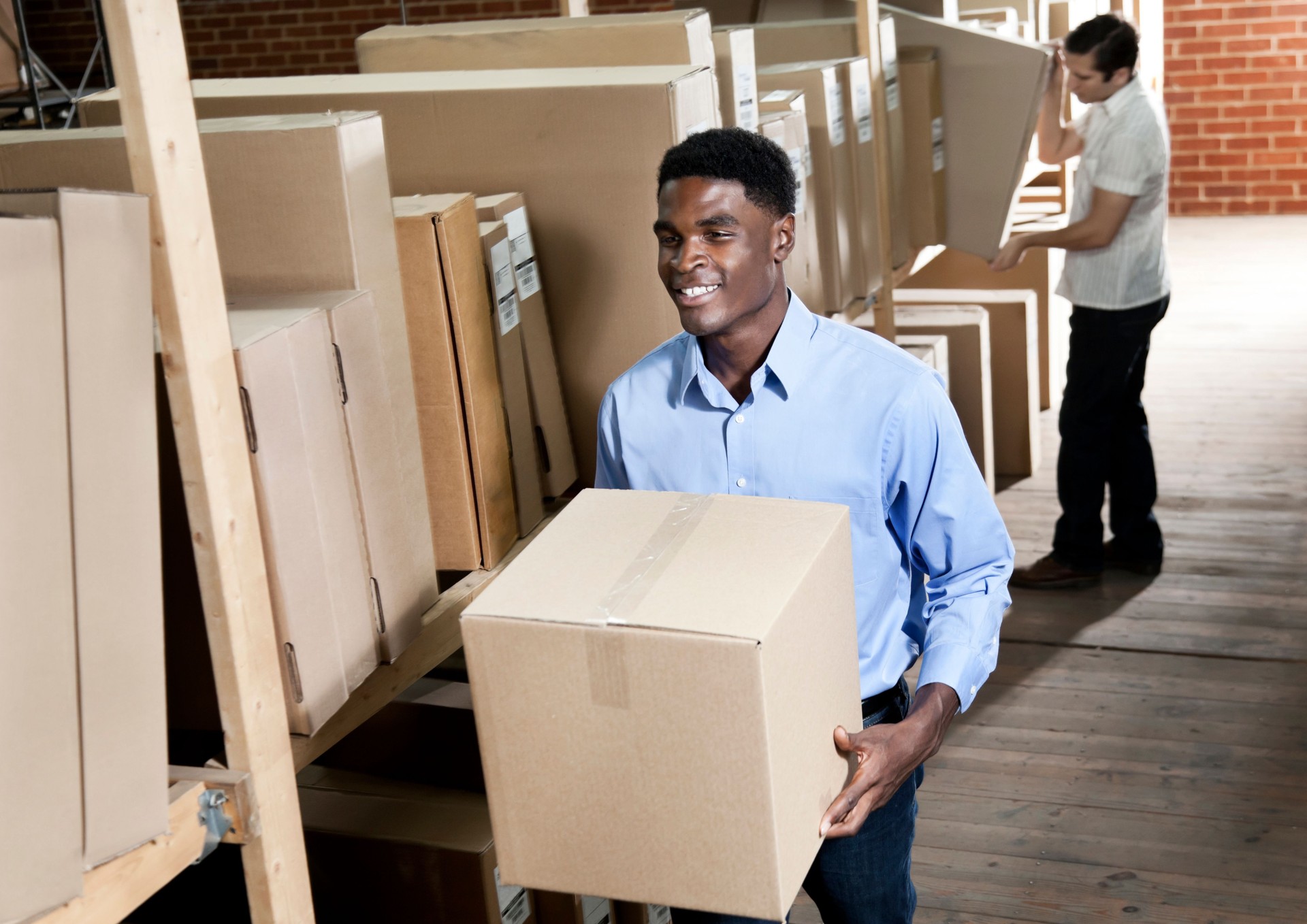 African American male carrying box in a storage room